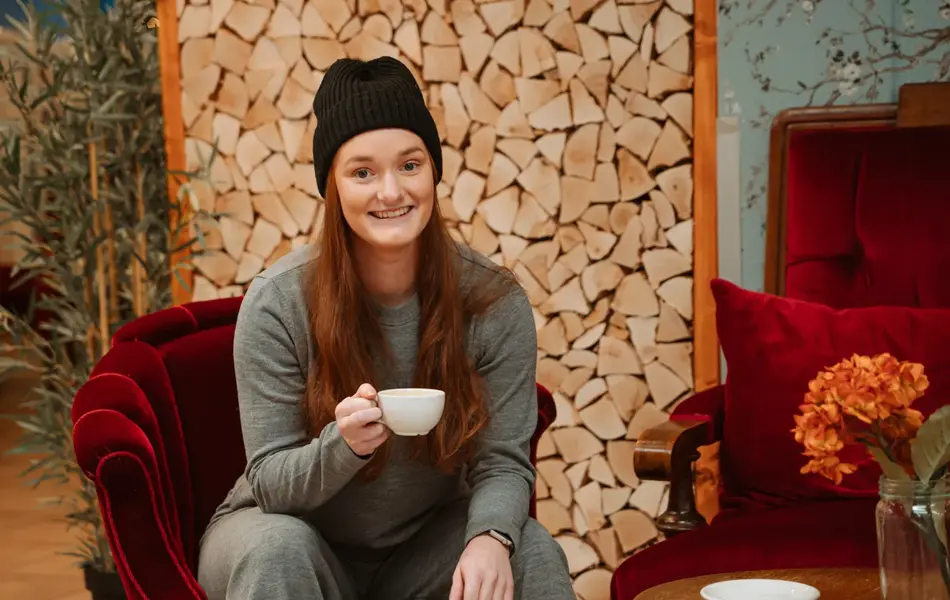 blid ansatt viser frem grå kosedress