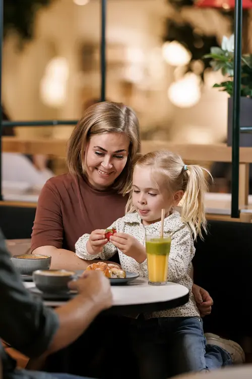 En mann, en kvinne og et barn sitter ved et bord på en kafé, barnet sitter på fanget til kvinnen 