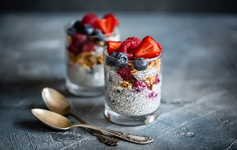 Healthy vanilla chia pudding in glass with fresh berries on vintage concrete table. Copy space. Banner.