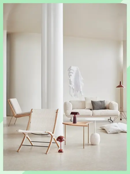 Stort rom med hvit sofa, to hvite stoler, lite sofabord, lamper og puter.