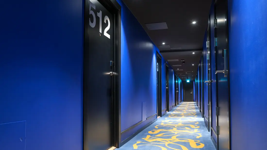 Kooridor med mønstret gulvteppe, blå vegger og store tall på dørene hos Thon Hotel Europa i Oslo sentrum rett ved Slottsparken