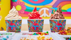 tre ulike frozen yoghurt i papp kopp stående på en disk med flere ulike topping