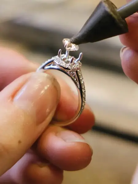 Noen som setter på plass en diamant på en ring