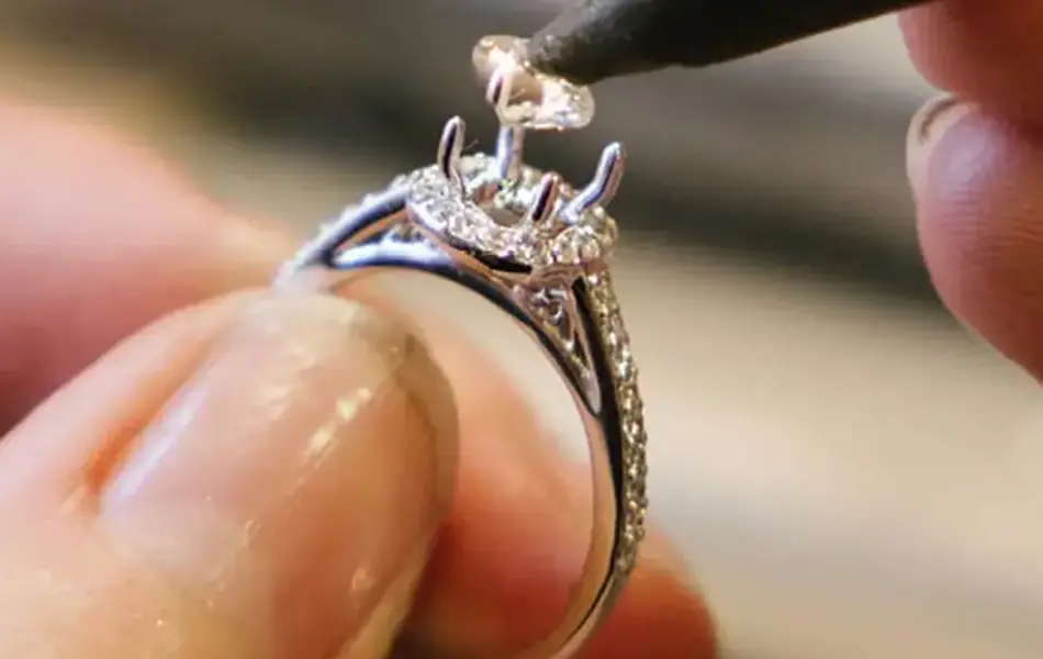 Noen som setter på plass en diamant på en ring