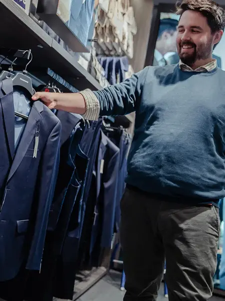 Bilde av en butikkansatt som viser frem en dress