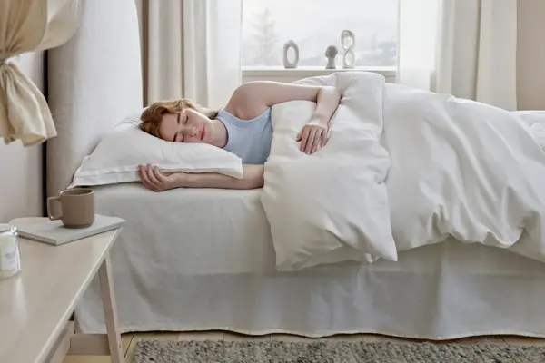 Dame som sover i en seng