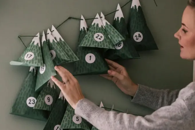 Dame henger opp julekalender på veggen