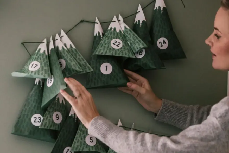 Dame henger opp julekalender på veggen