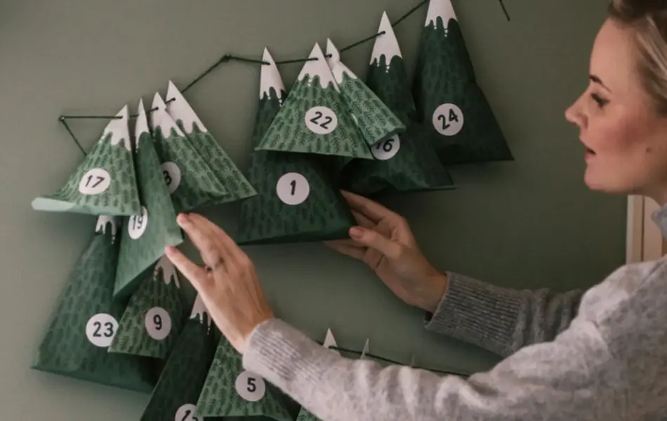 Dame henger opp julekalender på veggen