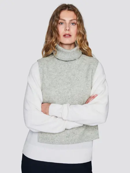 Kvinnelig modell som poserer i hvit genser med en strikket, grå hals o ver