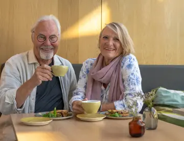 Eldre par nyter kaffe på lokal kafè 