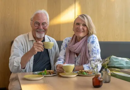 Eldre par nyter kaffe på lokal kafè 