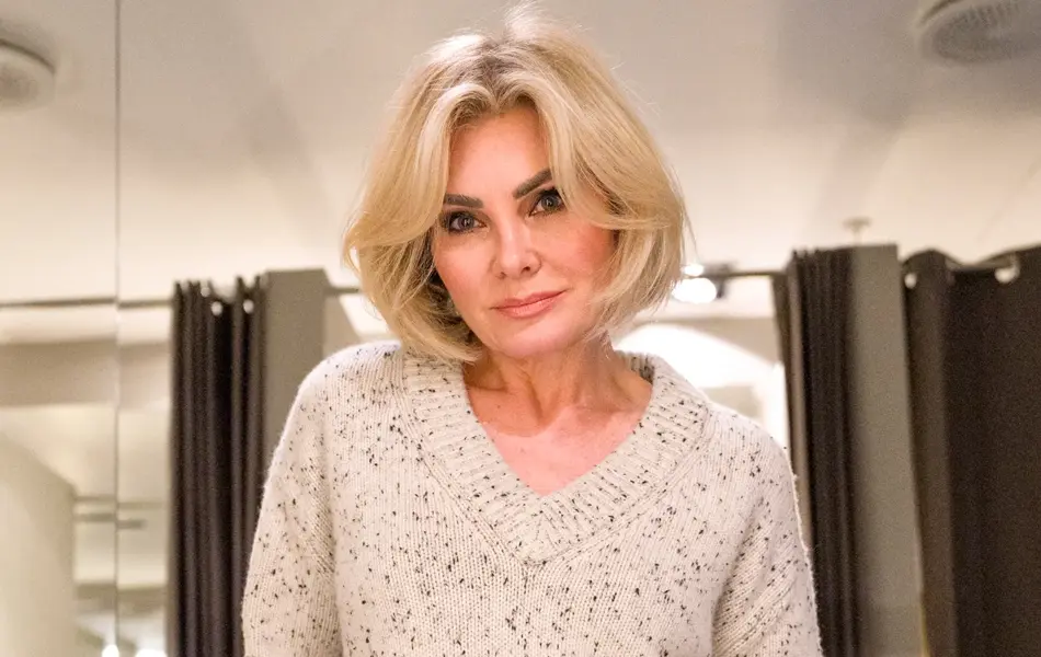 Dame i beige melert strikkegenser og hvite bukser