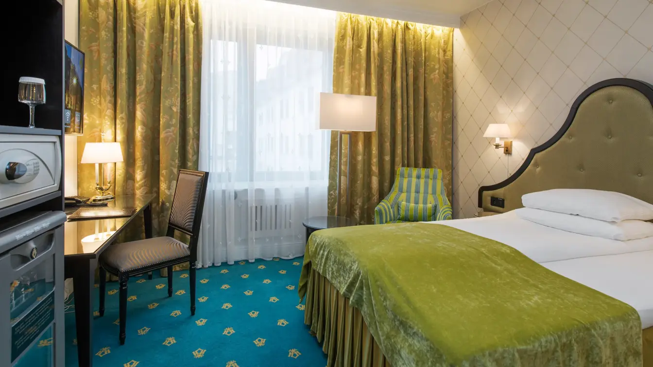 Stor seng med safe, skrivepult på Standard singelrom på Hotel Bristol i Oslo sentrum