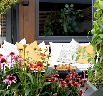 Detaljer fra en balkong med diverse planter og utemøbel med puter.
