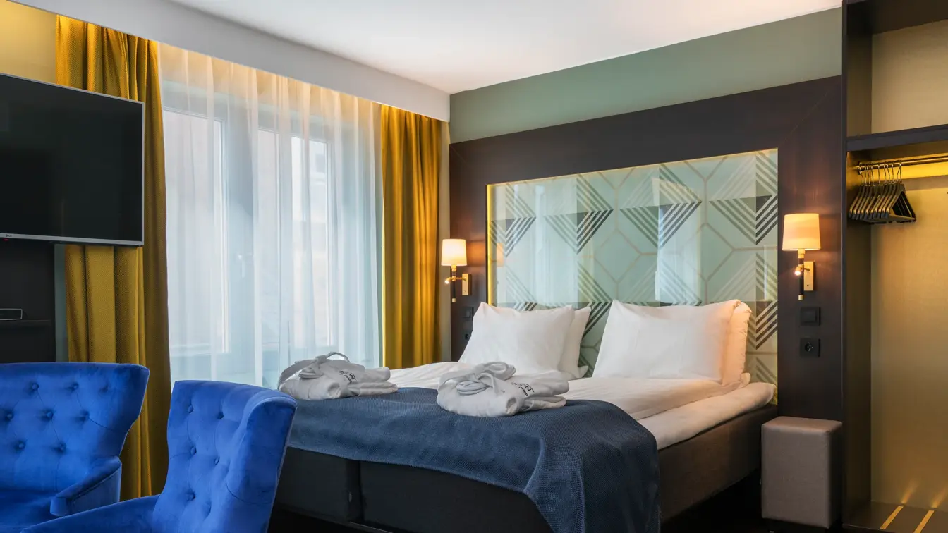 Dobbeltseng med morgenkåpe og tøfler, sittegruppe og smart-TV i businessrom på Thon Hotel Orion i Bergen sentrum. 