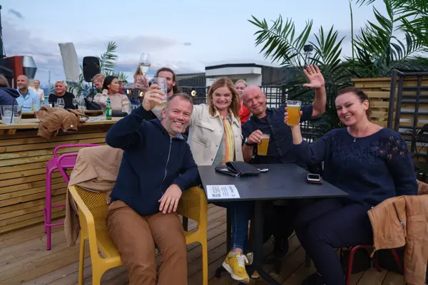 To menn og do damer skåler rundt et bord på utekonsert