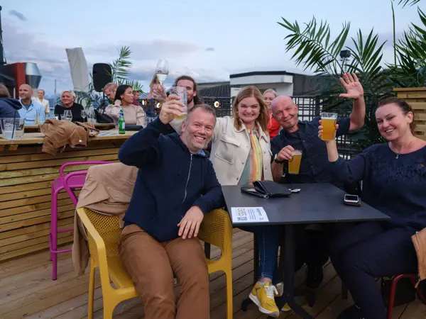 To menn og do damer skåler rundt et bord på utekonsert