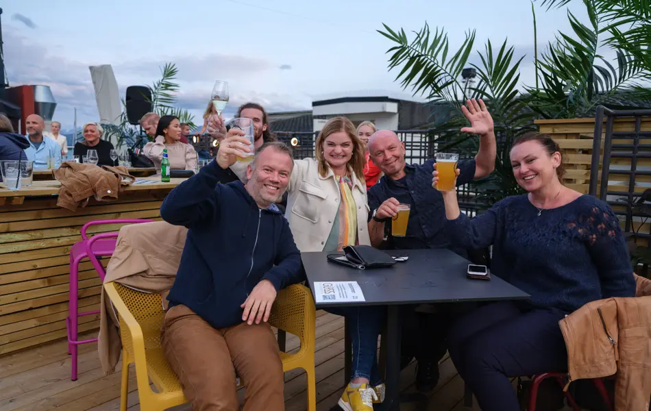 To menn og do damer skåler rundt et bord på utekonsert