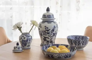 Blå- og hvitmønstret servise med vase, krukke og skåler på et spisebord.