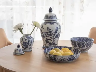 Blå- og hvitmønstret servise med vase, krukke og skåler på et spisebord.