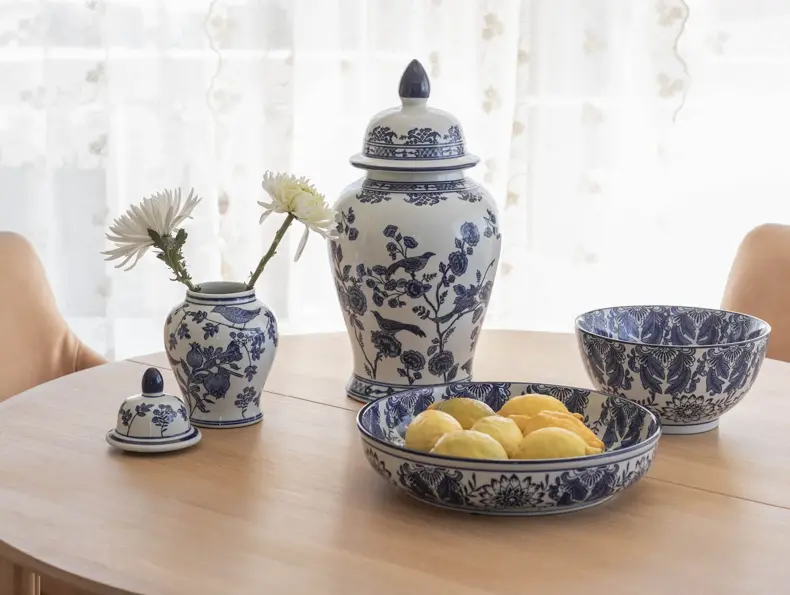 Blå- og hvitmønstret servise med vase, krukke og skåler på et spisebord.