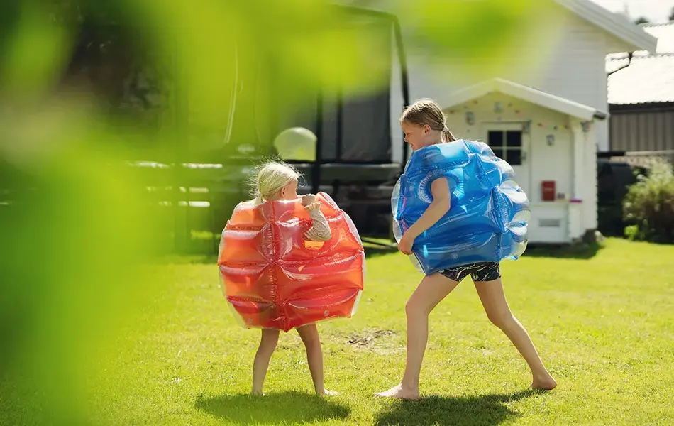 To jenter som leker ute i hage i sumobryter kostyme fraRingo