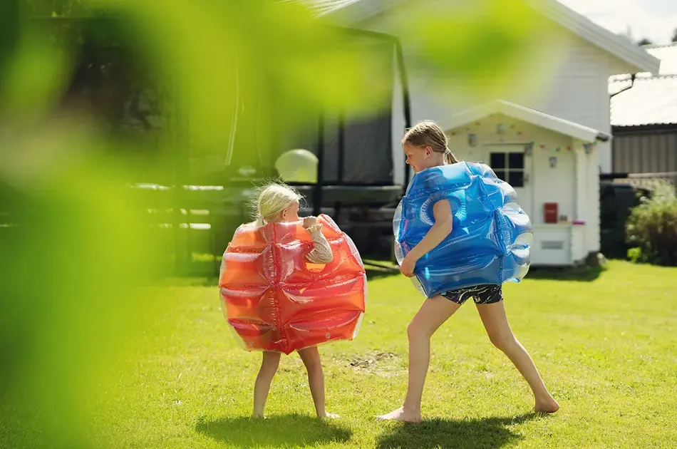 To jenter som leker ute i hage i sumobryter kostyme fraRingo