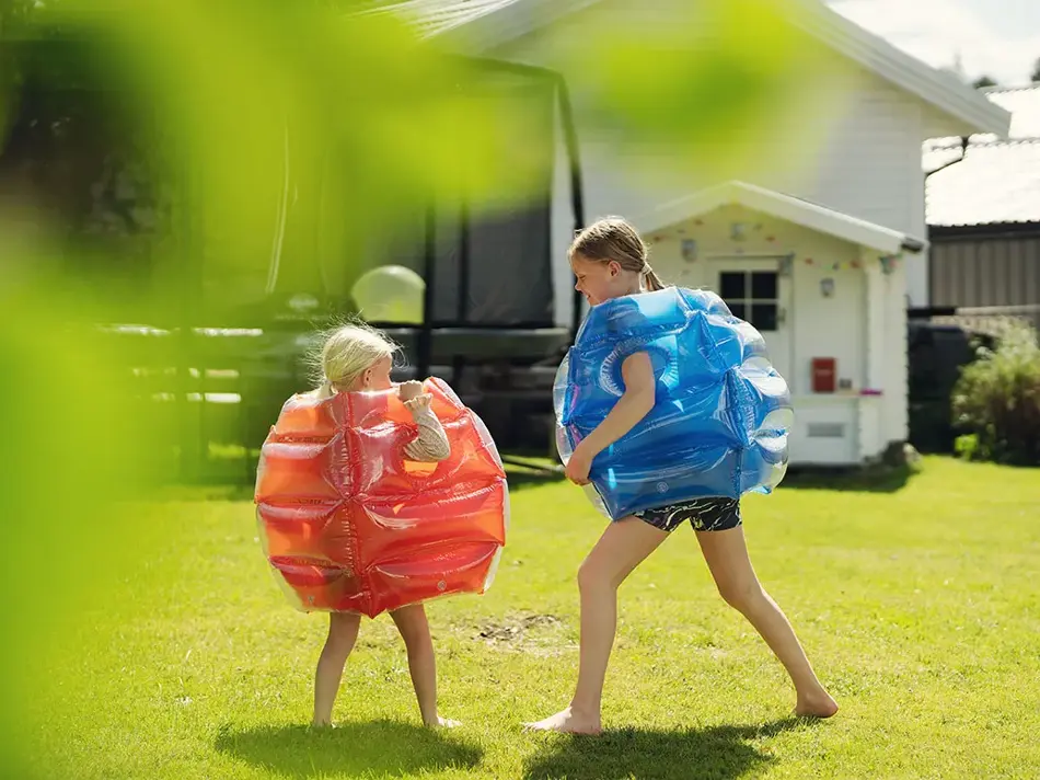 To jenter som leker ute i hage i sumobryter kostyme fraRingo