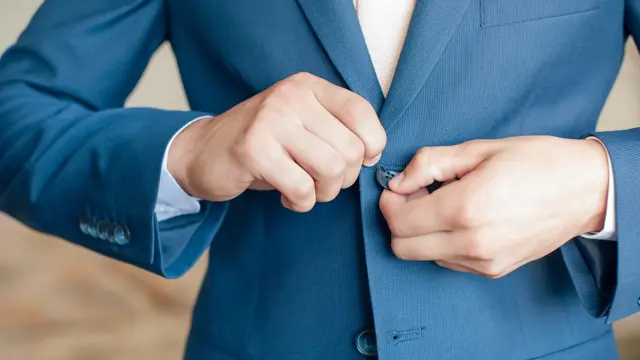 Nærbilde av hender som knepper igjen blazer