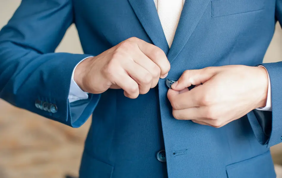 Nærbilde av hender som knepper igjen blazer