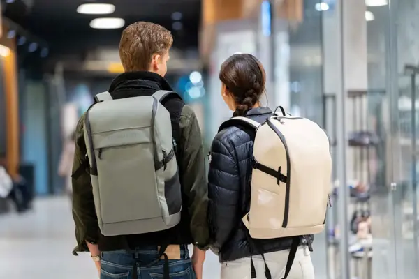 Tenåringsgutt med jakke og grå sekk, tenåringsjente med boblejakke og lysebeige sekk