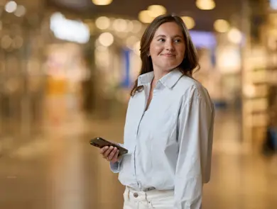 Dame i en gang på et kjøpesenter med en mobil. 