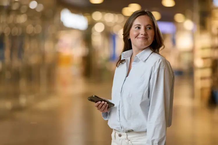 Dame i en gang på et kjøpesenter med en mobil. 