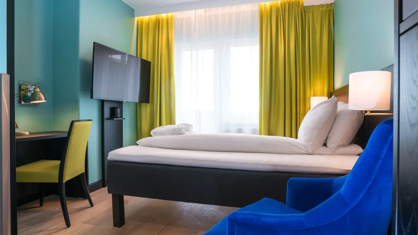 TV, skrivepult, dobbeltseng, lenestol på dobbelrom på Thon Hotel Europa i Oslo sentrum rett ved Slottsparken