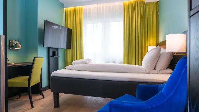 TV, skrivepult, dobbeltseng, lenestol på dobbelrom på Thon Hotel Europa i Oslo sentrum rett ved Slottsparken