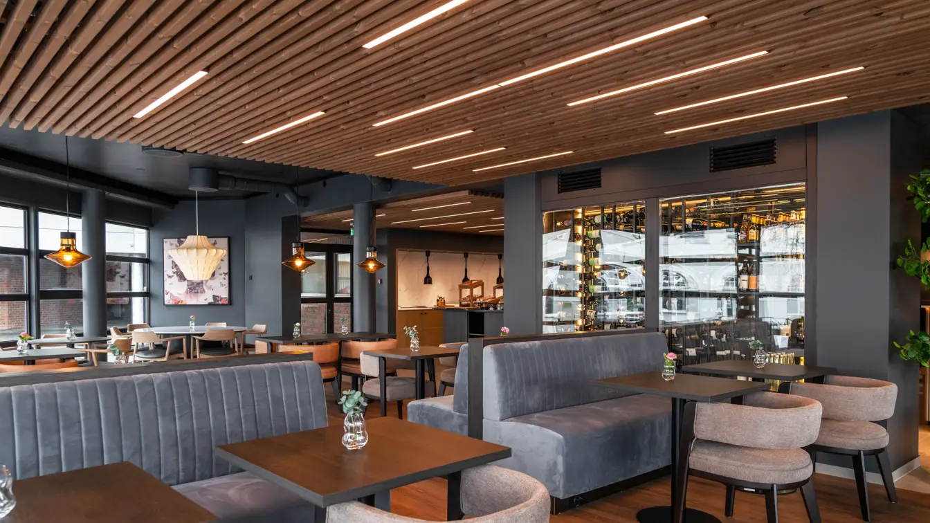 Frokostsal med firkantede bord, grå stoler og grå sittebenker.