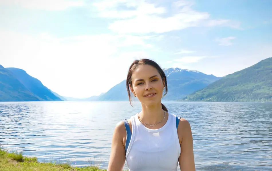anny johansen viser yogaøvelser ute foran vakker fjord