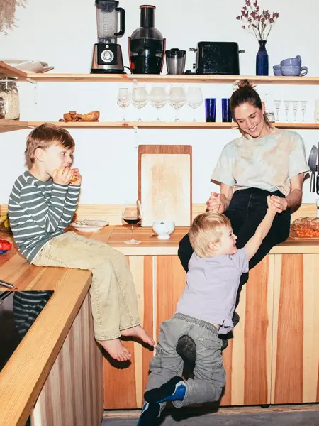 Familie med mor og to små gutter leker på kjøkken 