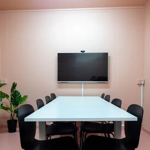 Møterom med rosa vegger og grønne planter.