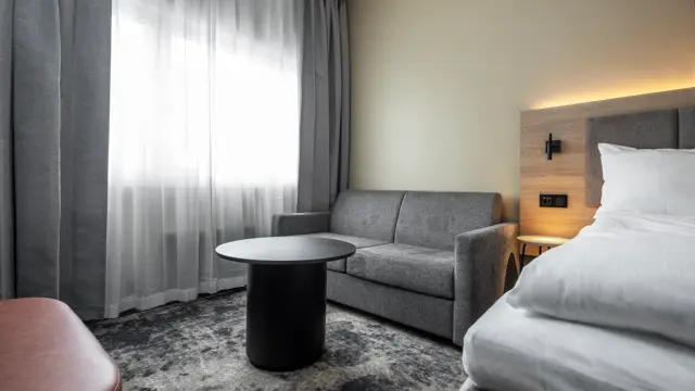 Dobbeltrom med dobbeltseng, sofa, bord, lange grå og hvite gardiner