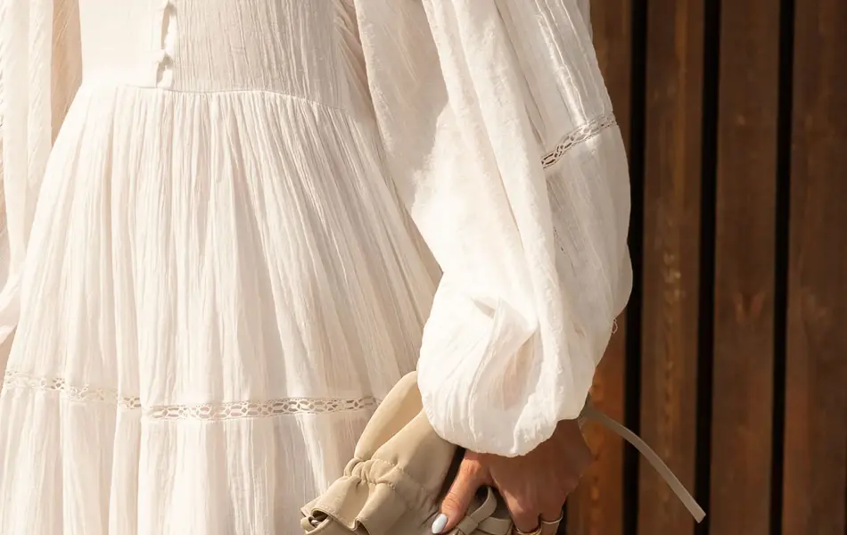 Dame i kjole som holder en håndveske