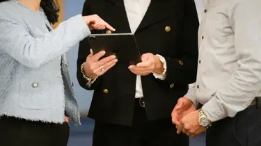 tre personer peker på en ipad