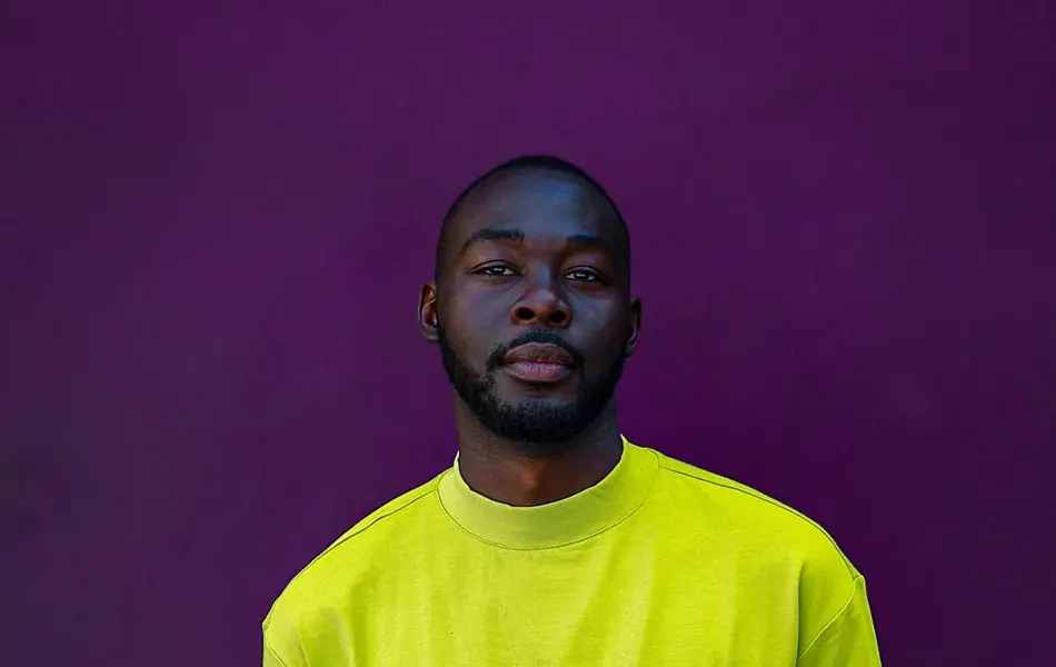 Mann i grønn t-skjorte foran lilla vegg