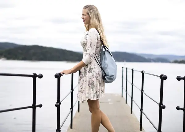 dame på brygge med bag på ryggen