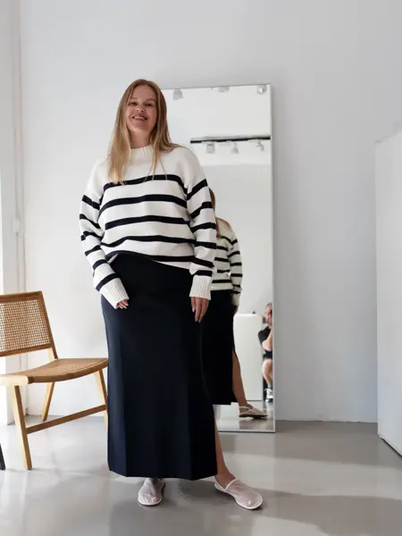 Damemodell med sort langt skjørt og hvit og sort stripet genser
