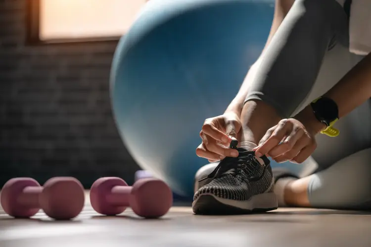 Cropped shot of an sportwoman tying her shoelaces in a gym