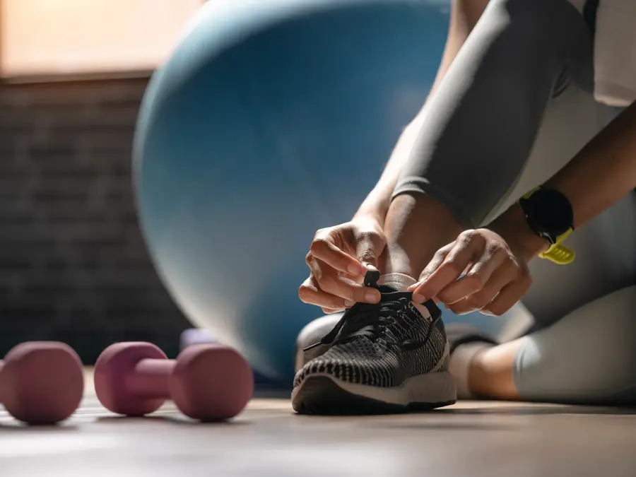 Cropped shot of an sportwoman tying her shoelaces in a gym