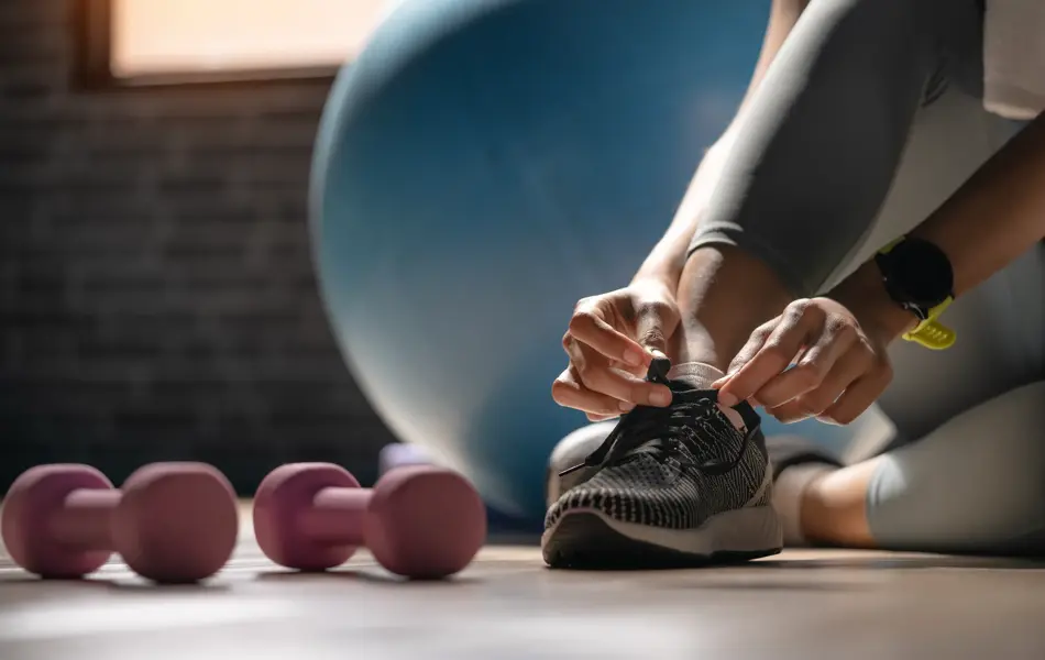 Cropped shot of an sportwoman tying her shoelaces in a gym