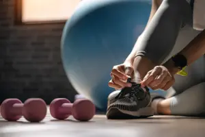 Cropped shot of an sportwoman tying her shoelaces in a gym